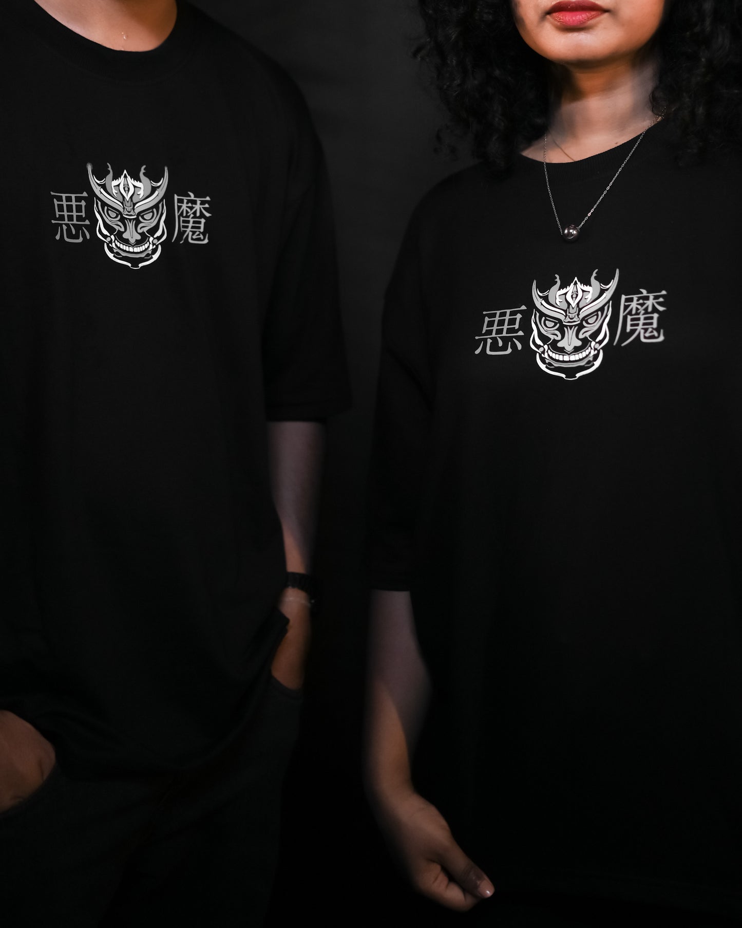 Suggestion
Two people wearing black t-shirts with a white logo and text on a dark background